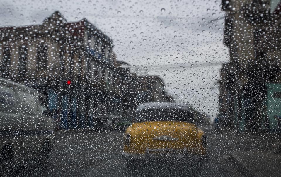 FILE - In this May 24, 2018 file photo, rain drops accumulate on a car's windshield as commuters wait at a red light in Havana, Cuba. (AP Photo/Desmond Boylan, File)