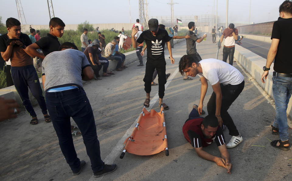 Protesters try to evacuate a wounded youth after inhaling teargas fired by Israeli soldiers during a protest at the entrance of Erez border crossing between Gaza and Israel, in the northern Gaza Strip, Tuesday, Sept. 4, 2018. The Health Ministry in Gaza says several Palestinians were wounded by Israeli fire as they protested near the territory's main personnel crossing with Israel. (AP Photo/Adel Hana)