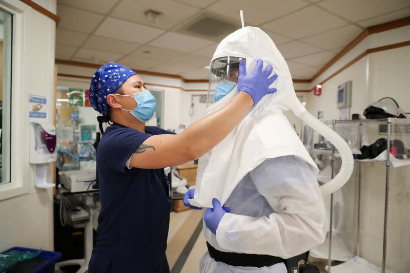 Zafia Anklesaria, codirectora de la unidad de cuidados intensivos en el Centro Médico del Hospital Dignity Health California de CommonSpirit, de 35 años y con siete meses de embarazo, se coloca un traje protector para atender a un paciente donde trabaja en medio del brote de coronavirus en Los Angeles, California, EEUU