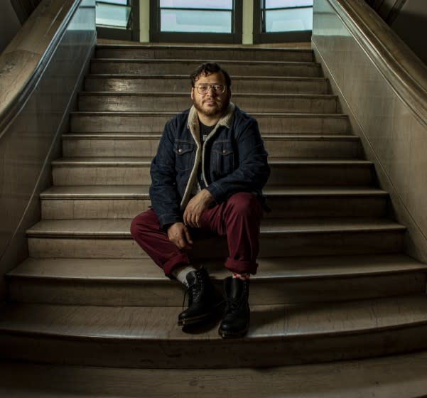 The writer christopher oscar peña sitting on the steps of his apartment building in downtown L.A.