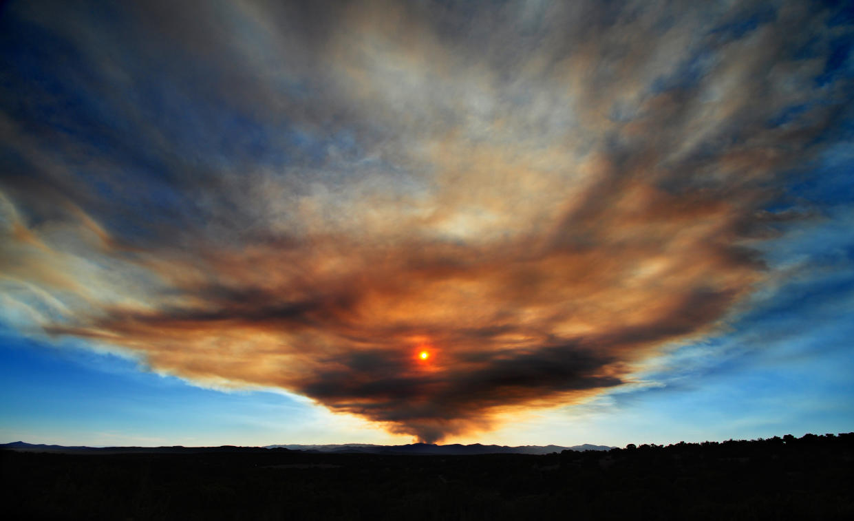 SANTA FE, NM - JUNE 1, 2013: The sun sets behind a towering plume of smoke from a forest fire in the Jemez Mountains, near Jemez Springs in Northern New Mexico west of Santa Fe. The blaze, known as the Thompson Ridge Fire, is burning in the Valles Caldera National Preserve. It ignited May 31 when a tree fell across a power line. (Photo by Robert Alexander/Getty Images) 5104602RA_NewMexicoFire03.jpg
