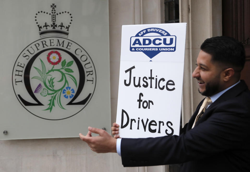 Uber driver and president of the (ADCU), App Drivers & Couriers Union, Yaseen Islam poses with a poster outside the Supreme Court in London, Friday, Feb. 19, 2021. The U.K. Supreme Court ruled Friday that Uber drivers should be classed as “workers” and not self employed.(AP Photo/Frank Augstein)