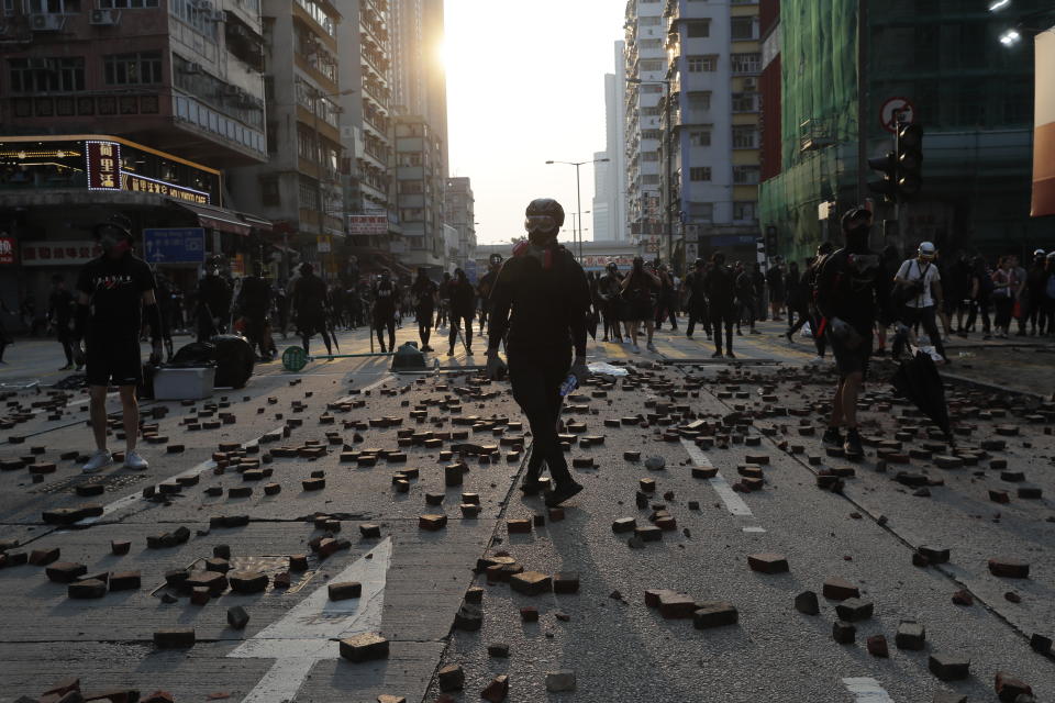 Protestors stand on scattered bricks as they clash with police in Hong Kong, Sunday, Oct. 20, 2019. Hong Kong protesters again flooded streets on Sunday, ignoring a police ban on the rally and setting up barricades amid tear gas and firebombs. (AP Photo/Kin Cheung)