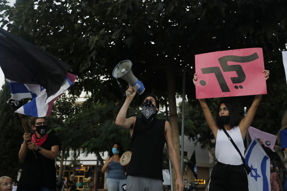 A woman holds a placard that reads, "go," during a protest against Prime Minister Benjamin Netanyahu in Tel Aviv, Israel, Thursday, Oct. 8, 2020 during a nationwide lockdown to curb the spread of the coronavirus. The Israeli government has extended an emergency provision that bars public gatherings, including widespread protests against Netanyahu, for an additional week. (AP Photo/Ariel Schalit)