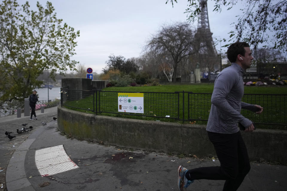 A man jogs past a blood stain on the scene where a man targeted passersbys late saturday, killing a German tourist with a knife and injuring two others in Paris, Sunday, Dec. 3, 2023. Police subdued the man, a 25-year-old French citizen who had spent four years in prison for a violent offense. After his arrest, he expressed anguish about Muslims dying, notably in the Palestinian territories. (AP Photo/Christophe Ena)