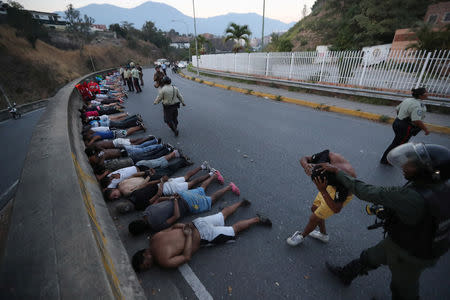 FILE PHOTO: People detained by security forces lie on the street after looting broke out during an ongoing blackout in Caracas, Venezuela, March 10, 2019. REUTERS/Ivan Alvarado