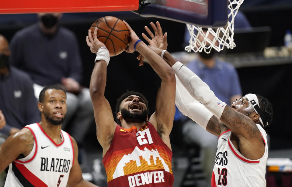 Denver Nuggets guard Jamal Murray, center, drives to the rim between Portland Trail Blazers guard Rodney Hood, left, and forward Robert Covington in the first half of an NBA basketball game on Tuesday, Feb. 23, 2021, in Denver. (AP Photo/David Zalubowski)