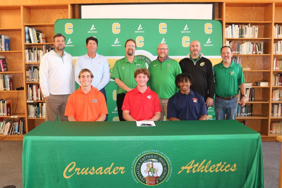 (Seated from left to right) Pensacola Catholic's Brock Clayton, Jackson Kohr and Chris Rembert pose for photos with Crusaders coaches after signing his letters of intent to play baseball collegiately on Wednesday, Nov. 8, 2023 from Pensacola Catholic High School.