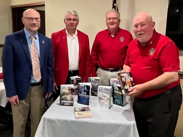 Eric Taggart, left, director of Rodman Public Library, was presented with nine large-print books by Alliance Lions Club Rose Sale Chairman Bill Prueter, Lions Club President Allen Kahler and top salesman Bill Morris, who sold 249 dozen roses.