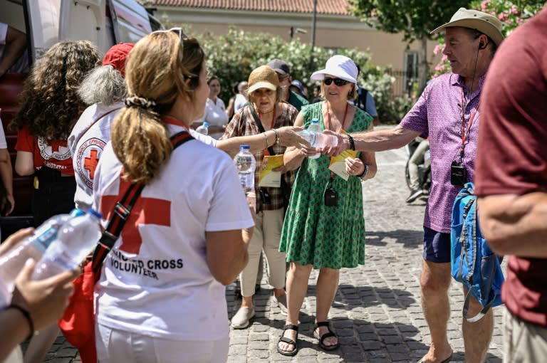 Volunteers of the Hellenic Red Cross hand out bottles of water at the Acropolis hill in Athens in July 2023 as Greece was hit by a heatwave (Spyros BAKALIS)