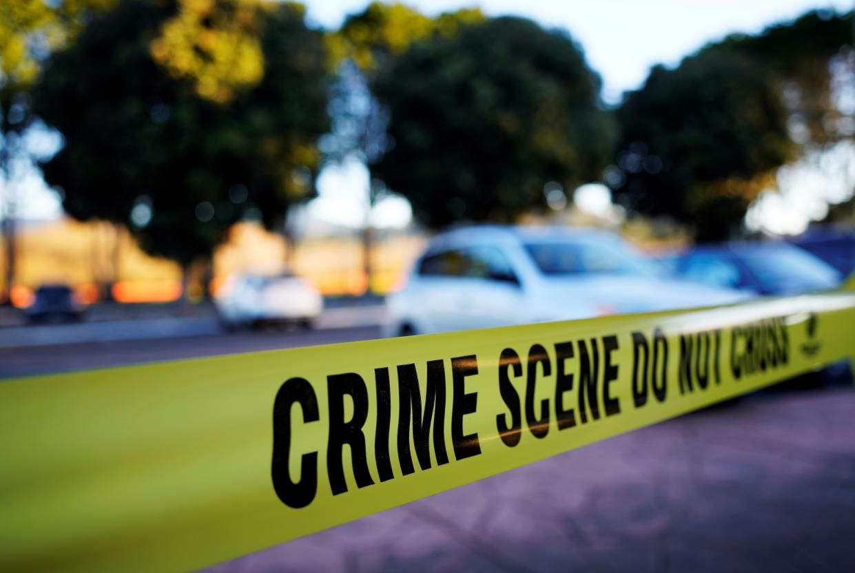 Yellow police tape cordoning off a parking lot says: Crime Scene, Do Not Cross!