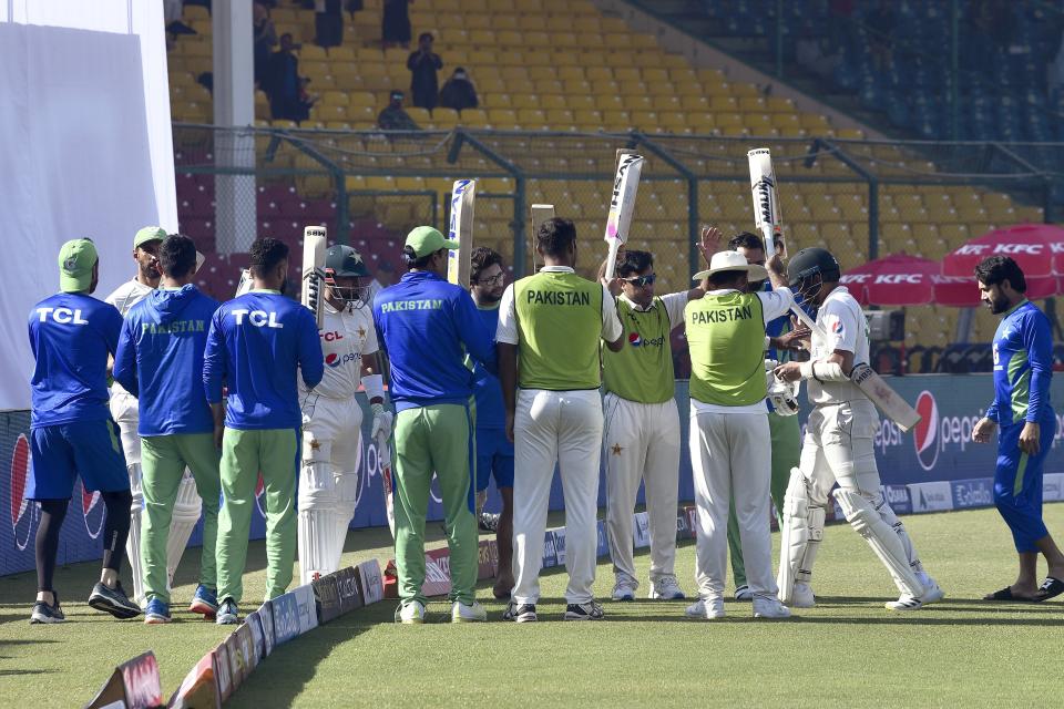 Pakistani players give guard of honor to teammate Azhar Ali, center, who is playing his last match due to his retirement, after his dismissal during the third day of third test cricket match between England and Pakistan, in Karachi, Pakistan, Monday, Dec. 19, 2022. (AP Photo)