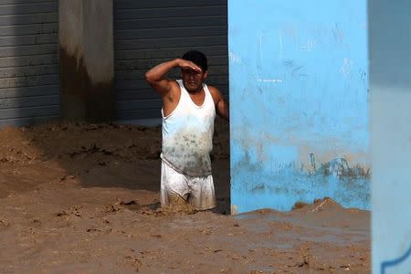 Un hombre mira desde una calle inundada de Huachipa en Lima. 17 de marzo de 2017. REUTERS/Guadalupe Pardo