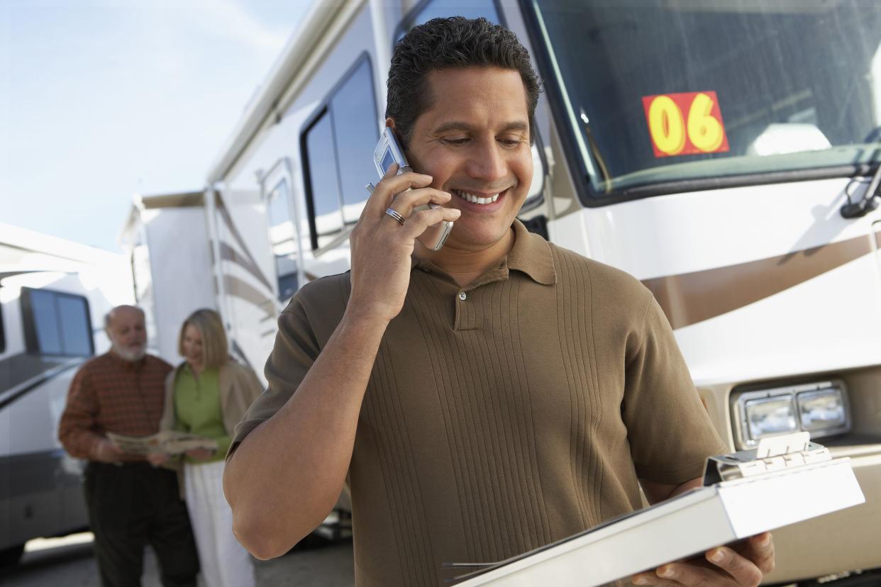 salesperson on cell phone while couple shops for an rv