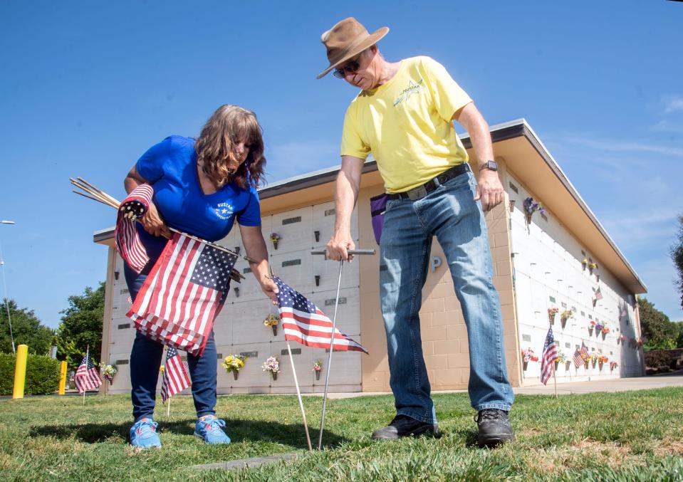 (5/25/22)Volunteers Carol Roschewski, left, and Michael Kelley wit Nu Star Energy, placed some of the thousands of flags at veterans' graves ahead of Memorial Day services at Cherokee Memorial Park in Lodi. The service starts at 10:30 a.m. on Monday, May 30 at the cemetery on Harney Lane and Highway 99 in Lodi. The event will feature a gun salute, a dove release and a missing-man formation fly-by. CLIFFORD OTO/THE STOCKTON RECORD