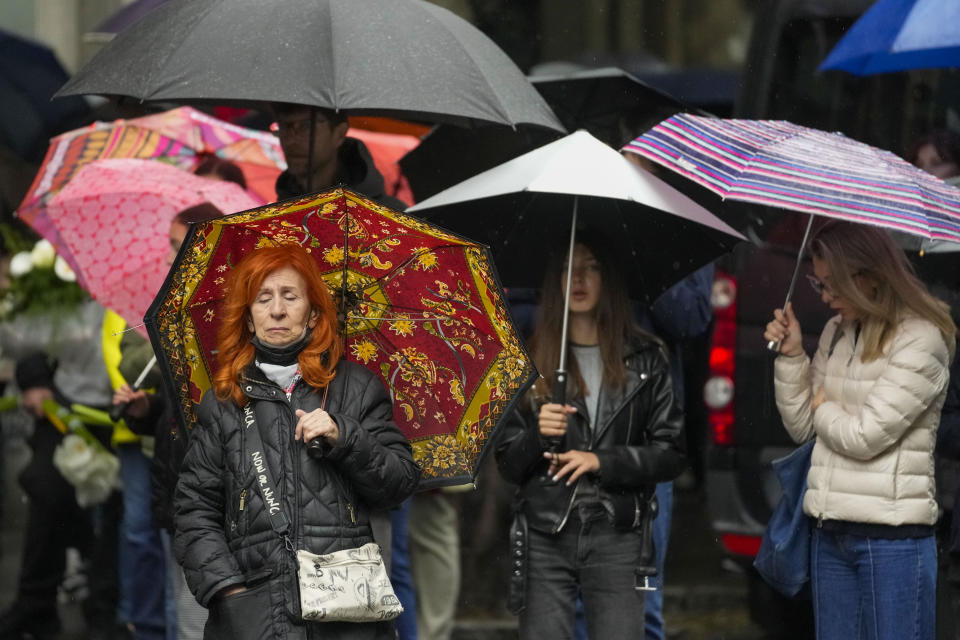 People gather in front of the Vladislav Ribnikar school during a memorial ceremony to mark the first anniversary of a shooting that killed 10 people in Belgrade, Serbia, Friday, May 3, 2024. (AP Photo/Darko Vojinovic)