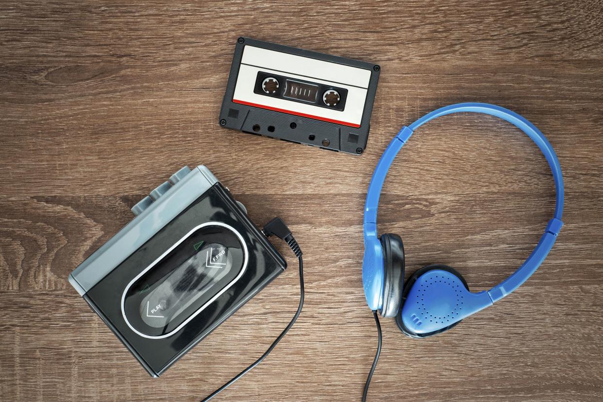 Vintage walkman, cassette tape, and blue headphones on a wooden background