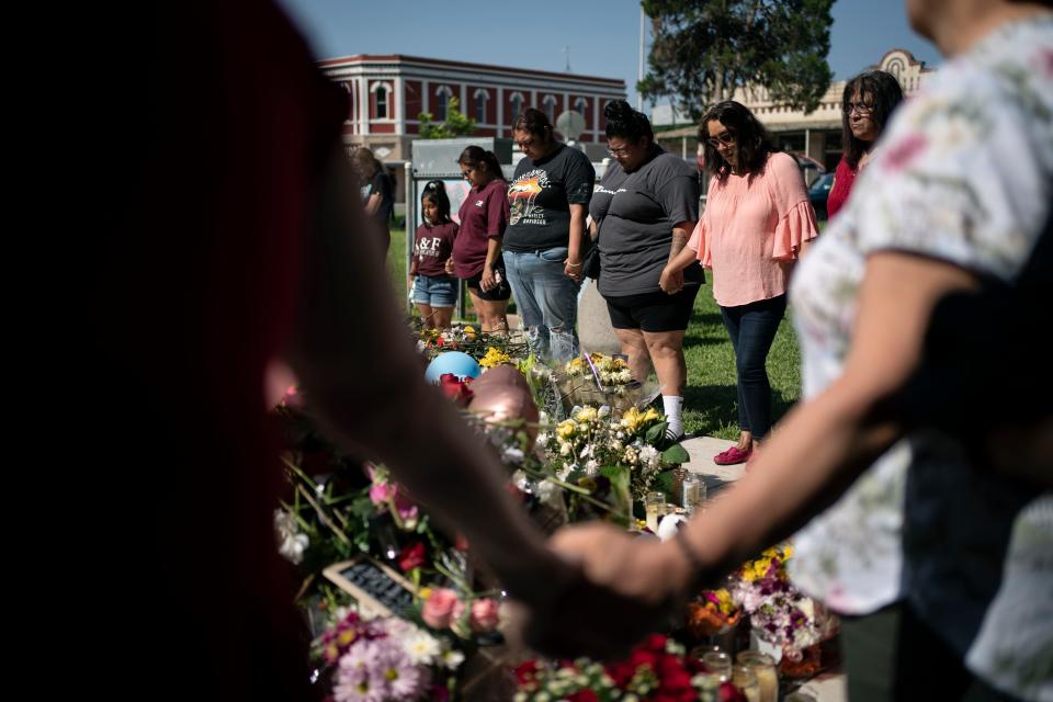 McKenzie Hinojosa, 28, fourth from left, prays for her cousin Eliahana Torres and other victims, at a memorial site for victims killed in the Robb Elementary school shooting, Saturday, May 28, 2022, in Uvalde, Texas. (AP Photo/Wong Maye-E)