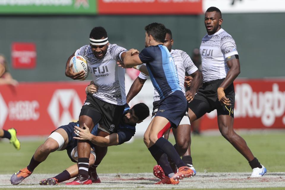 Fiji's Vilimoni Botitu runs with the ball as Argentina's players try to stop him during a match of the Emirates Airline Rugby Sevens in Dubai, United Arab Emirates, Friday, Dec. 6, 2019. (AP Photo/Kamran Jebreili)