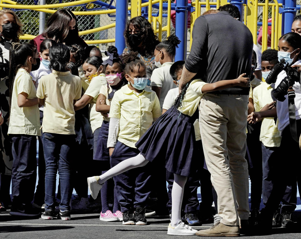 Meghan, the Duchess of Sussex, background left, and Prince Harry, foreground right, interact with students during their visit to P.S. 123, the Mahalia Jackson School, in New York's Harlem neighborhood, Friday, Sept. 24, 2021. (AP Photo/Richard Drew)