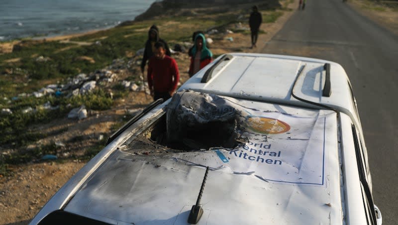 Palestinians inspect a vehicle with the logo of the World Central Kitchen wrecked by an Israeli airstrike in Deir al Balah, Gaza Strip, Tuesday, April 2, 2024. A series of airstrikes killed seven aid workers from the international charity, leading it to suspend delivery Tuesday of vital food aid to Gaza.