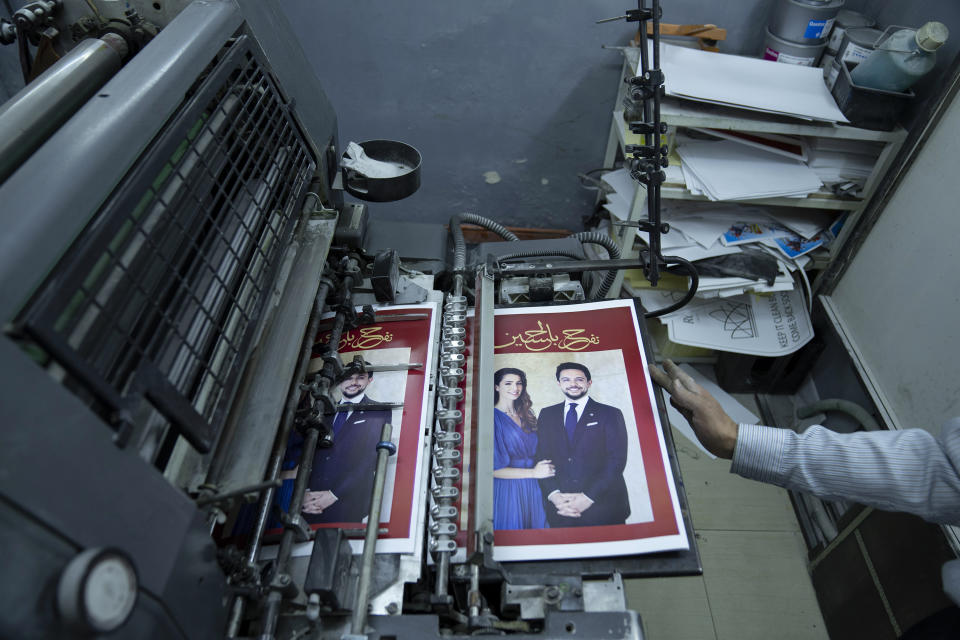 A Jordanian specialist follows the process of printing posters with pictures of Crown Prince Hussein and his fiancee, Saudi architect Rajwa Alseif and reads "we celebrate Hussein," at a print house in Amman, Jordan, Wednesday, May 31, 2023. Crown Prince Hussein and Saudi architect Rajwa Alseif are to be married on Thursday at a palace wedding in Jordan, a Western-allied monarchy that has been a bastion of stability for decades as Middle East turmoil has lapped at its borders.(AP Photo/Nasser Nasser)