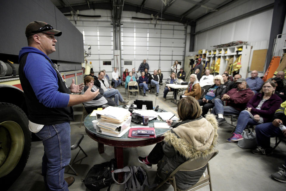 In this Oct. 24, 2019 photo, volunteer fire department chief and village trustee Zachary Klein briefs residents during a town hall meeting at the fire hall in Winslow, Neb where relocating the village was discussed. It took only minutes for swift-moving floods from the Elkhorn River to ravage tiny Winslow this spring, leaving nearly all its 48 homes and businesses uninhabitable. Now, the couple dozen residents still determined to call the place home are facing a new challenge: Moving the entire town about three miles away to higher ground. (AP Photo/Nati Harnik)