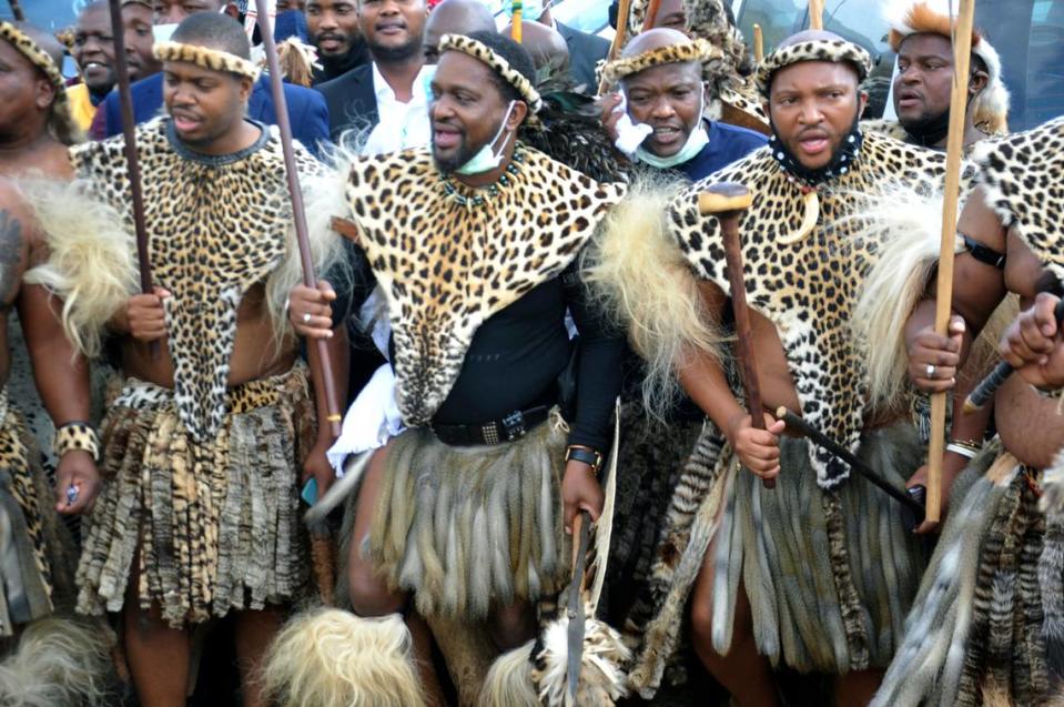 Prince Misuzulu Zulu, centre, flanked by fellow warriors in traditional dress at the KwaKhangelamankengane Royal Palace, during a ceremony, in Nongoma, Friday May 7, 2021. A new Zulu king in South Africa has been named amid scenes of chaos as other members of the royal family questioned Prince Misuzulu Zulu’s claim to the title. He was suddenly whisked away from the public announcement at a palace by bodyguards. The controversy over the next king has arisen after the death in March of King Goodwill Zwelithini, who had reigned since 1968. Zwelithini apparently named one of his six wives, Queen Mantfombi Shiyiwe Dlamini Zulu, as the “regent of the Zulu kingdom” in his will. But her death just over a week ago after holding the title for only a month has thrown the royal succession into turmoil. (AP Photo)