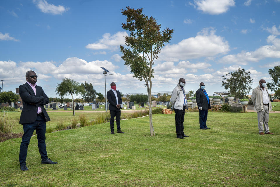 Family and friends observe social distancing during the funeral ceremony for Benedict Somi Vilakasi at the Nasrec Memorial Park outside Johannesburg Thursday, April 16, 2020. Vilakasi, a Soweto coffee shop manager, died of COVID-19 infection in a Johannesburg hospital Sunday April 12 2020. South Africa is under a strict five-week lockdown in a effort to fight the Coronavirus pandemic. (AP Photo/Jerome Delay)