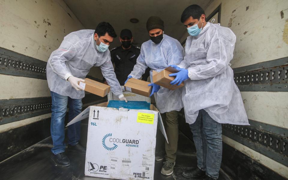 Palestinian workers unload the first shipment of Sputnik V Covid-19 vaccines from Israel, on the Palestinian side of the Kerem Shalom border crossing, south of Rafah, Gaza, on Wednesday Feb. 17. Israel has approved the shipment of Russian-made Sputnik coronavirus vaccine to Gaza - Ahmad Salem/Bloomberg