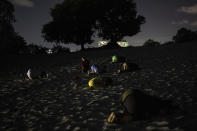 Women prostrate themselves in an area of the Abaete dune system, on a steep rise of sand evangelicals have come to call the "Holy Mountain", in Salvador, Brazil, late Friday night, Sept. 16, 2022. Evangelicals have been converging on the dunes for some 25 years but especially lately, with thousands now coming each week to sing, pray and enter trancelike states to commune with God. (AP Photo/Rodrigo Abd)