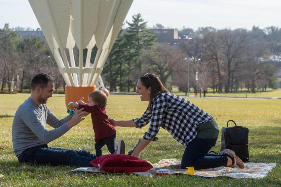 Jesus and Jennifer Clavo enjoy the warm Christmas Eve weather with their daughter, Camila, beneath a shuttlecock sculpture outside the Nelson-Atkins Museum of Art on Friday. The couple said they wanted to take advantage of the record warm weather. They don’t miss the snow.