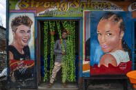 Jean Claude, 27, poses in front of his hairdressing salon in Goma, Democratic Republic of Congo, Saturday Nov. 26, 2022.At a time of tension and economic uncertainty, the bold names and brightly colored storefronts bring a sense of normalcy to residents who have contended with conflict and natural disasters such as volcanic eruptions for decades. (AP Photo/Jerome Delay)