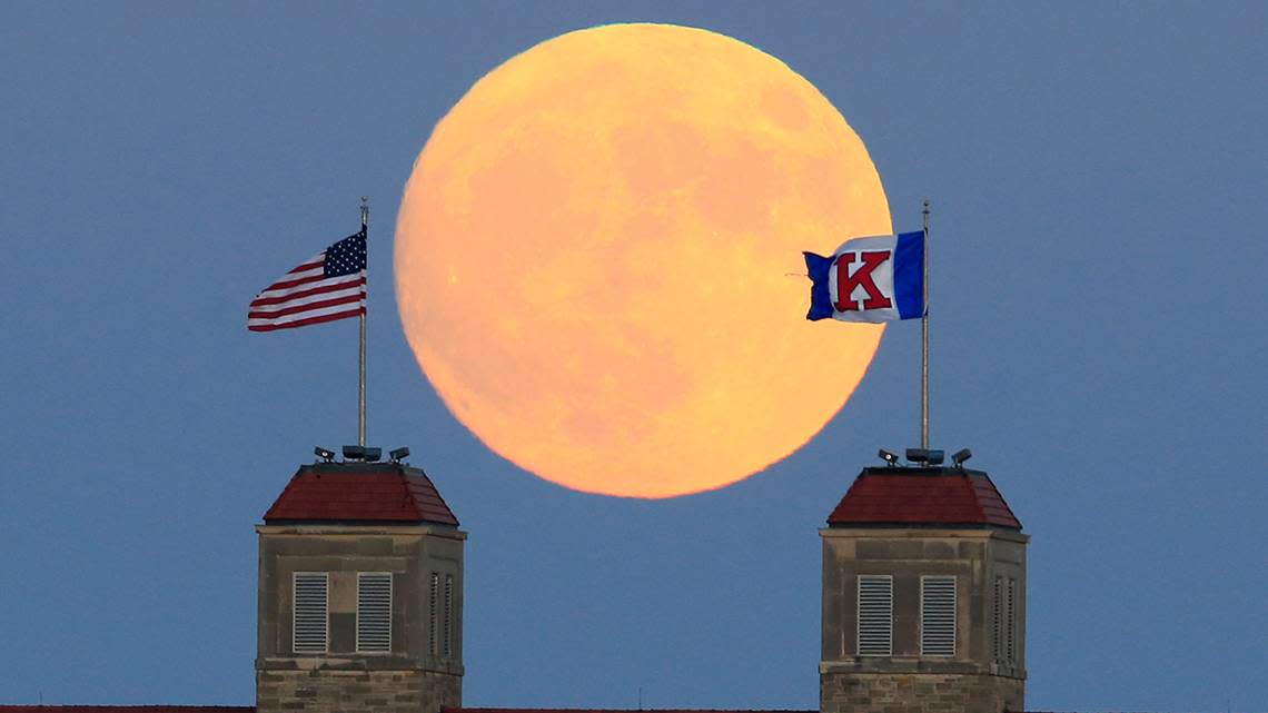 The moon rises beyond flags atop Fraser Hall on the University of Kansas campus in Lawrence, Kan., Sunday, Nov. 13, 2016. (AP Photo/Orlin Wagner)