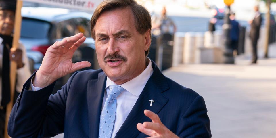 mypillow ceo mike lindell speaks to reporters on a sidewalk with his hands raised