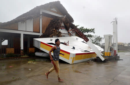 A resident runs past a collapsed roof of a petrol station after Typhoon Haima struck San Nicolas, Ilocos Norte in northern Philippines, October 20, 2016. REUTERS/Ezra Acayan