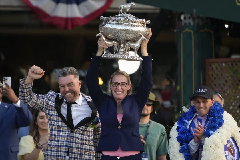 Trainer Jena Antonucci, center, hoists up the August Belmont Trophy alongside jockey Javier Castellano.