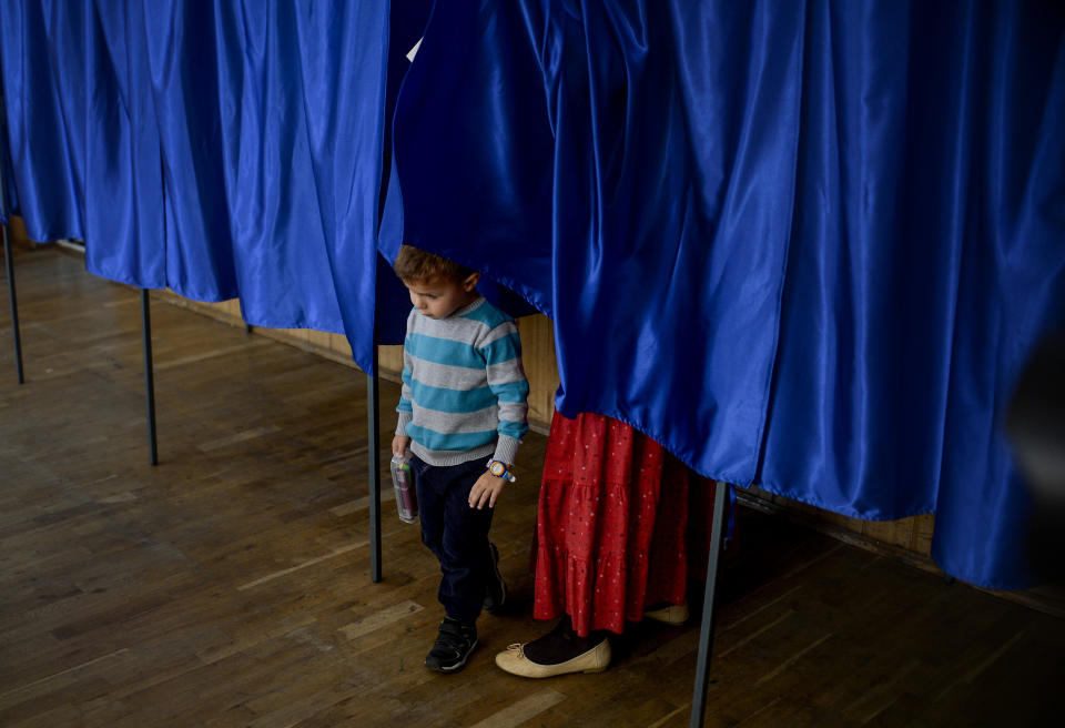 A child exits a voting cabin followed by his mother, in Ciorogarla, Romania, Sunday, Oct. 7, 2018. Romanians are voting Sunday around the country for a second day on a constitutional amendment that would make it harder to legalize same-sex marriage. (AP Photo/Andreea Alexandru)