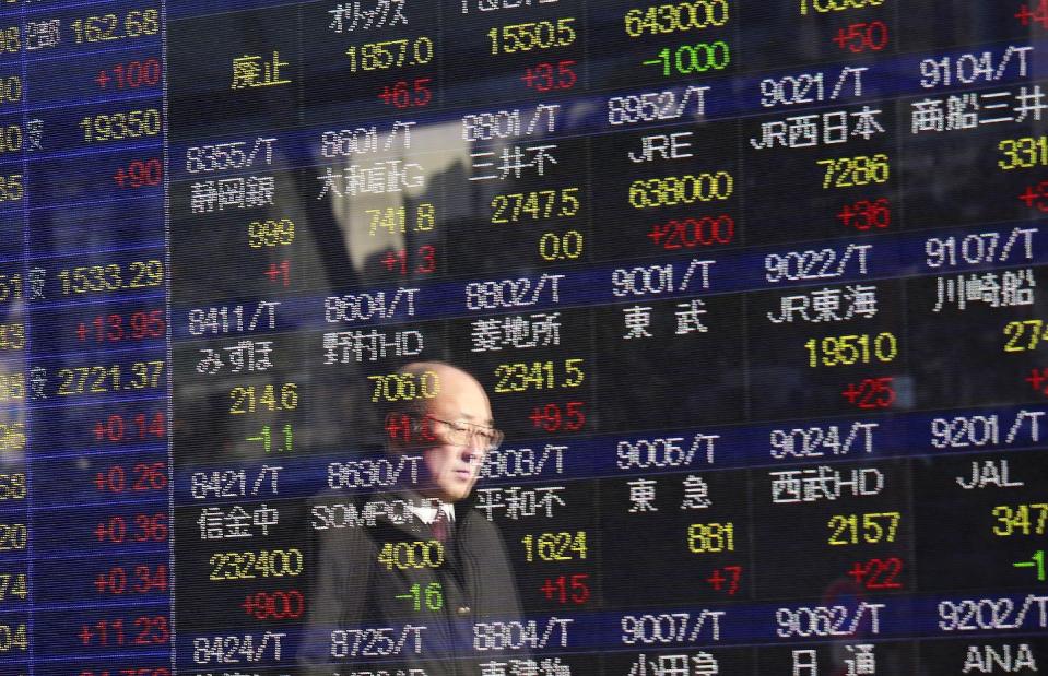 A man is reflected on an electronic stock indicator of a securities firm in Tokyo, Wednesday, Dec. 28, 2016. Shares meandered in quiet trading in Asia on Wednesday after the Dow Jones industrial average inched closer to 20,000 and the Nasdaq Composite rose to a record high.(AP Photo/Shizuo Kambayashi)