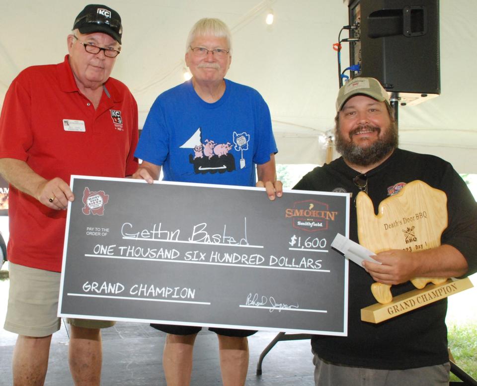Brad Leighninger, right, leader of the Gettin' Basted barbecue team from Branson, Missouri, accepts a plaque and first-place check for winning the Grand Championship on Day 1 of the 2023 Death's Door Bar-B-Q competition on Washington Island. Shown with Leighninger are, from left, Bill Gage of the Kansas City Barbeque Society, which sanctions the event, and Death's Door organizer Dick Jepsen.