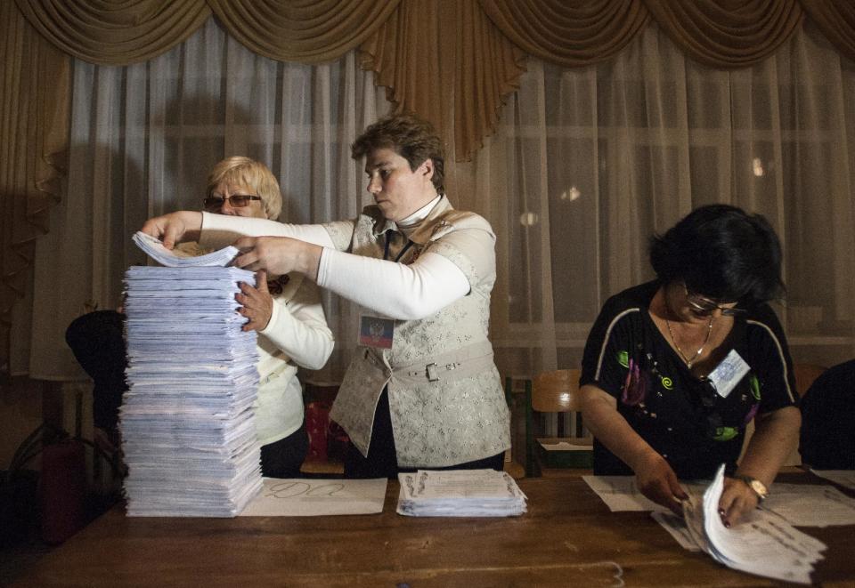 Members of election committee empty a ballot box after voting closed at a polling station in Donetsk, Ukraine, Sunday, May 11, 2014. Voters in two insurgent Ukrainian regions cast ballots Sunday on whether to declare their areas sovereign republics, a move denounced by the central government and likely to deepen the turmoil in the largely Russian-speaking east. (AP Photo/Evgeniy Maloletka)