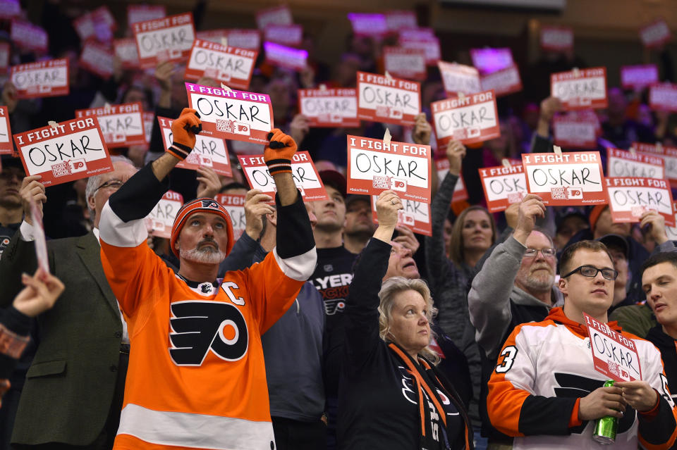 Fans hold signs in support of Philadelphia Flyers' Oskar Lindblom during a stoppage in the first period of an NHL hockey game against the Anaheim Ducks, Tuesday, Dec. 17, 2019, in Philadelphia. (AP Photo/Derik Hamilton)