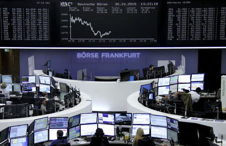 Traders are pictured at their desks in front of the DAX board at the stock exchange in Frankfurt, Germany, October 30, 2015. REUTERS/Staff/remote