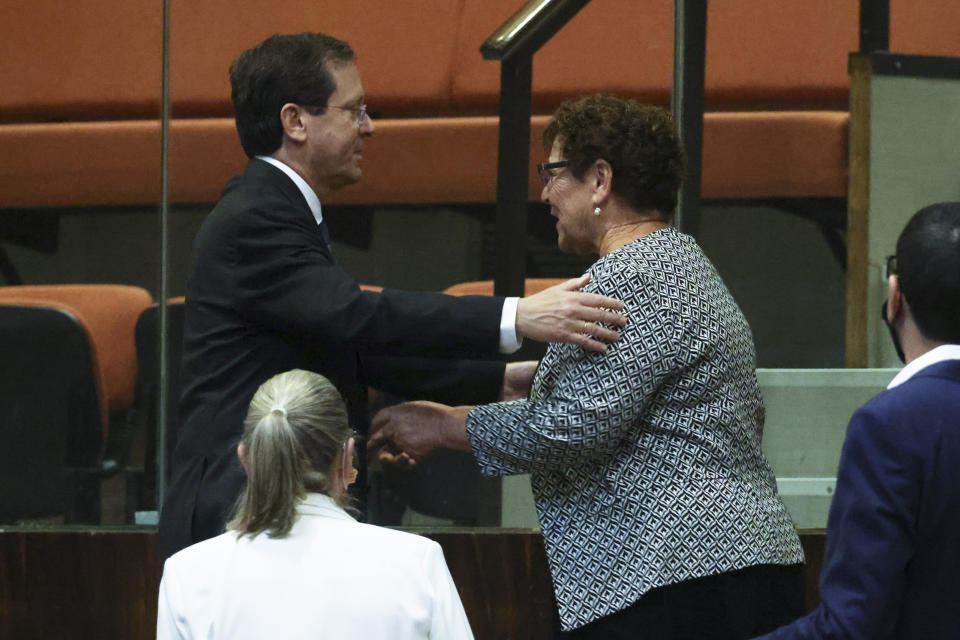 Presidential candidates Isaac Herzog, left, and Miriam Peretz greet each other during a special session of the Knesset, whereby Israeli lawmakers elect a new president, at the plenum in the Knesset, Israel's parliament, in Jerusalem on Wednesday, June 2, 2021. (Ronen Zvulun/Pool Photo via AP)