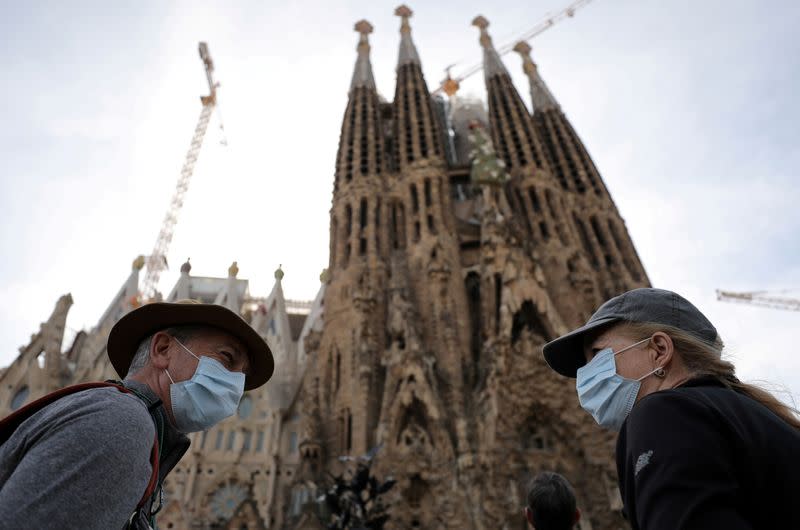 Tourists wear protective face masks as they talk in front of landmark Sagrada Familia basilica, in Barcelona