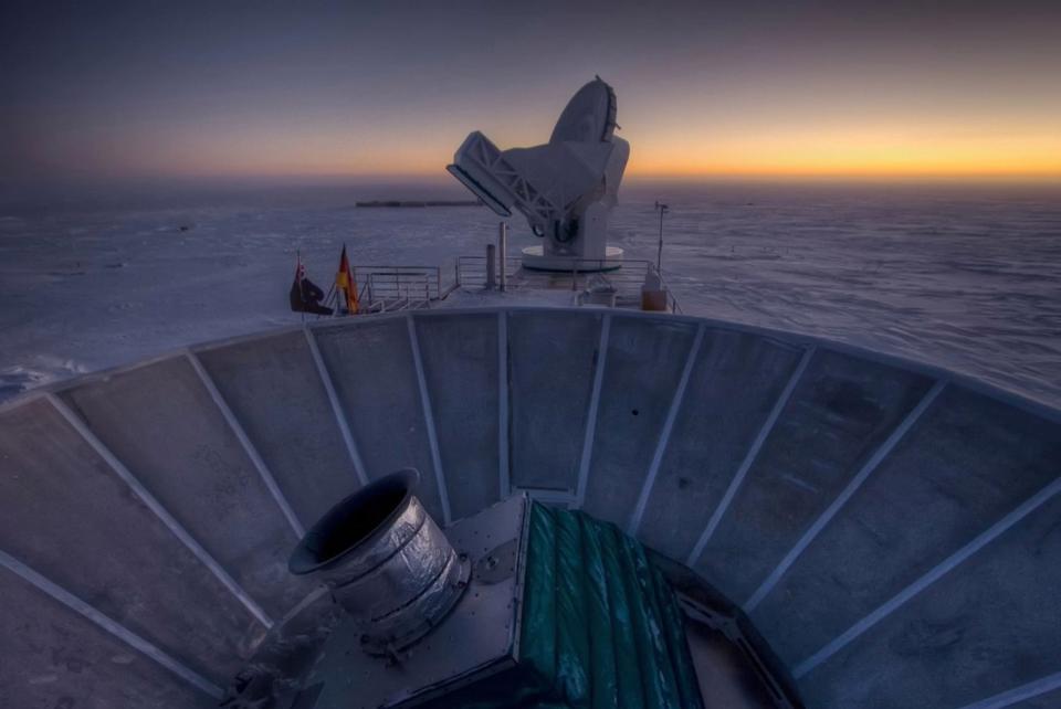 The sun sets behind BICEP2 telescope in the foreground. The South Pole Telescope stands in the background. <cite>Steffen Richter/Harvard University</cite>