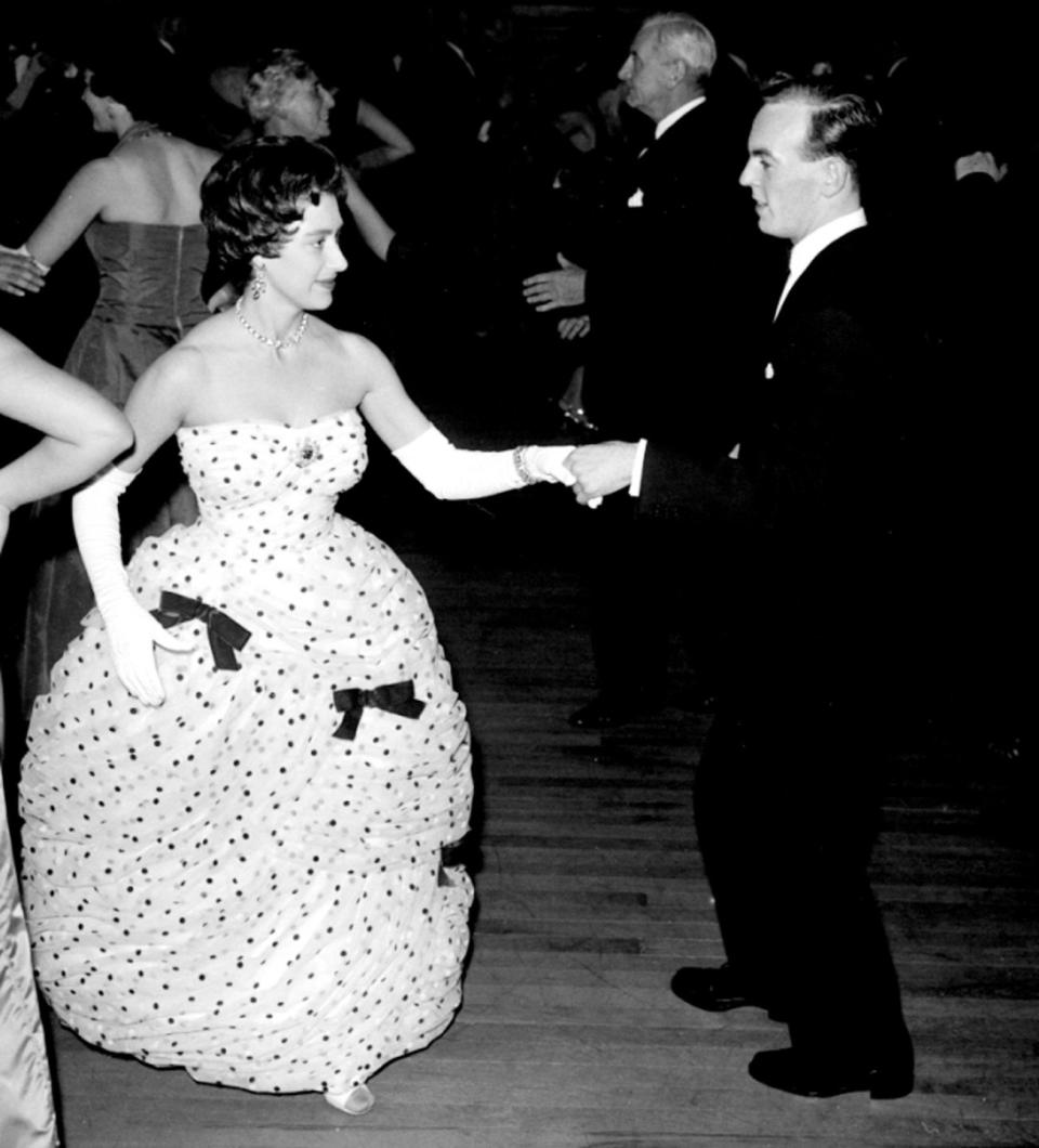 <p>Princess Margaret dances with Jackie Toaduff at a 1958 ball hosted by the English Folk Dance and Song Society. The Princess wore a balloon-skirted dress decorated with bows. </p>