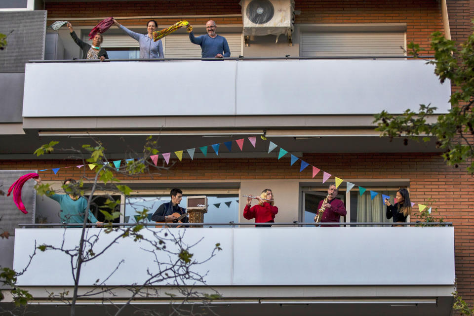 People play instruments as others dance on their balconies in support of the medical staff that are working on the COVID-19 virus outbreak in Barcelona, Spain, April 5, 2020. (AP Photo/Emilio Morenatti, File)