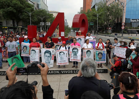 FILE PHOTO: Relatives pose with images of some of the 43 missing Ayotzinapa College Raul Isidro Burgos students in front of a monument of the number 43, during a march to mark the 41st month since their disappearance in the state of Guerrero, in Mexico City, Mexico February 26, 2018. REUTERS/Henry Romero