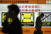 People walk past a public awareness sign for social distancing to help reduce the spread of the coronavirus Tuesday, June 22, 2021, in Tokyo. The Japanese capital confirmed more than 430 new coronavirus cases on Tuesday. (AP Photo/Eugene Hoshiko)